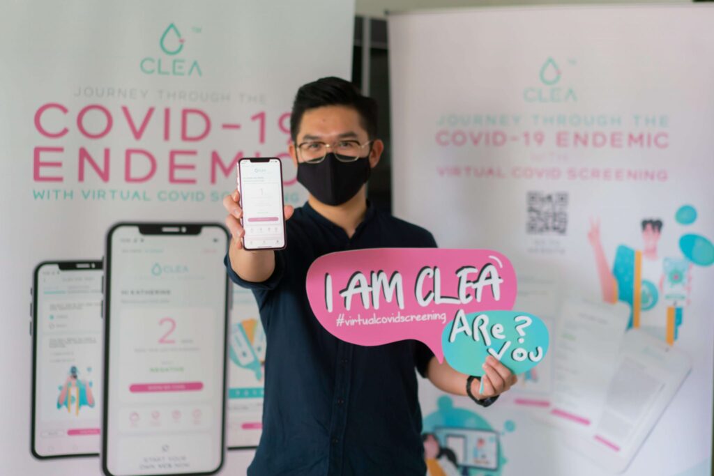 Man holding a phone showing the CLEA virtual COVID screening app at a launch booth