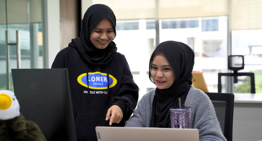 Two Elliot & Co. team members collaborating at a laptop in the Malaysia office