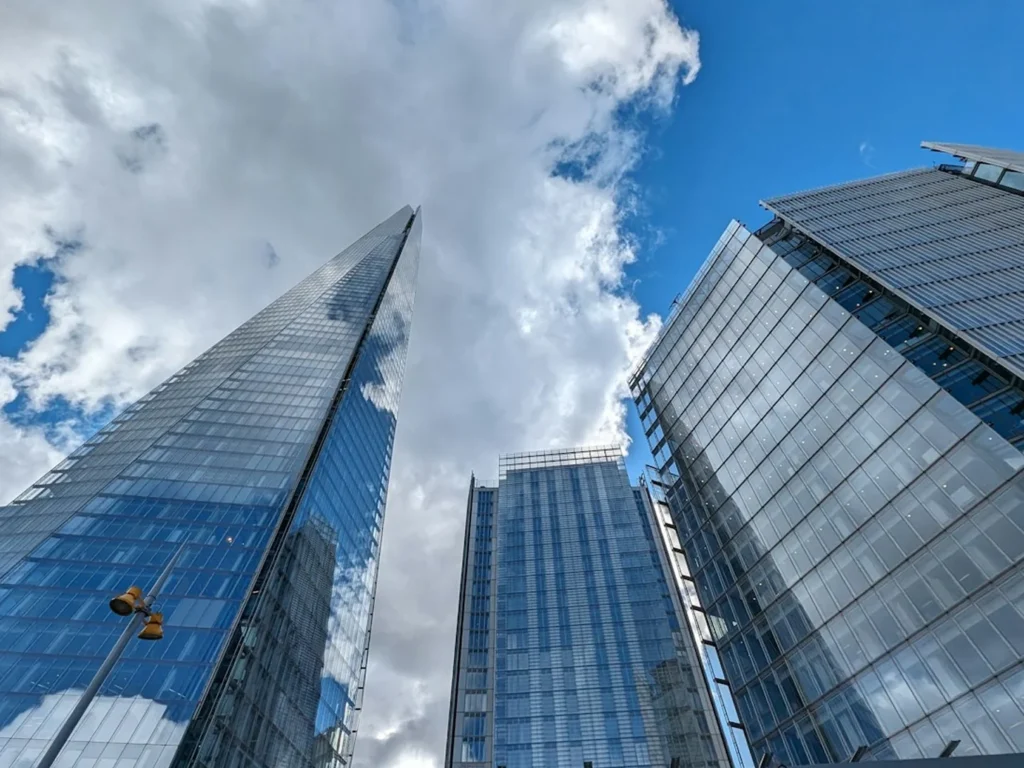 Modern glass office towers rising into a cloudy blue sky in a financial district