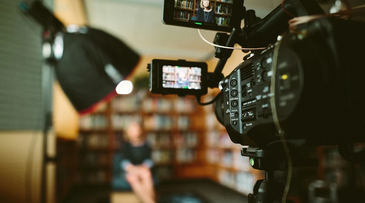 Video camera and lighting setup filming an interview in a library for PR media coverage