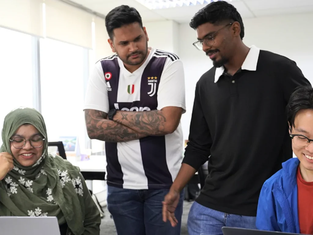 Elliot & Co. Malaysia team collaborating around laptops in a Kuala Lumpur office