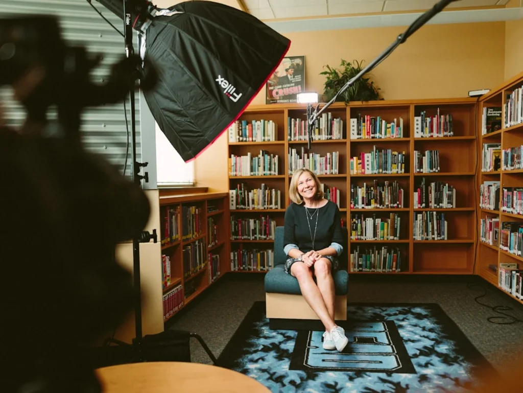 Media interview shoot with studio lighting and a spokesperson seated in a library